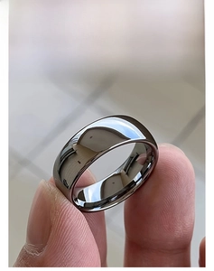Close-up of polished silver plain band ring showing high-gloss mirror finish and smooth arc