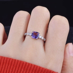 Princess cut amethyst open ring with white zircon accents on model's hand with red cuff