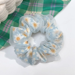 Detail of light blue daisy print scrunchie with sheer mesh layer on white background