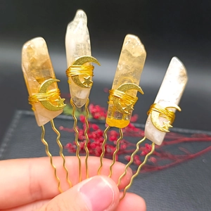 Detailed view of handmade moon and star hairpins with natural crystals and gold wire wrapping