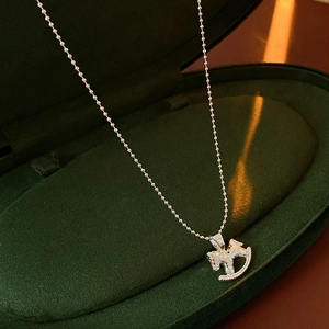 Gros plan d'un collier pendentif cheval à bascule argenté dans un écrin vert foncé chic
