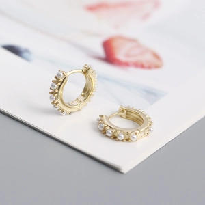 Macro detail of gold hoop earrings with small pearls and S925 silver stamp on interior