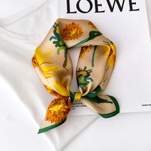 Detail of silk scarf with yellow sunflower pattern and green border on magazine backdrop