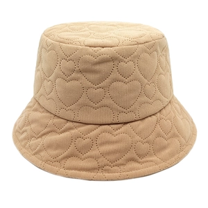 Detailed view of beige corduroy bucket hat with quilted heart patterns and knit texture