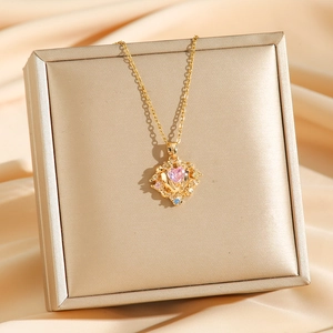 Golden titanium steel heart necklace with pink zircon stone on silk fabric background
