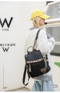 Close-up of black nylon backpack with leopard print flap and stylish tassel detail
