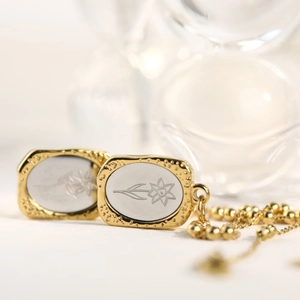 Macro shot of 18K gold-plated double pendants with intricate white floral engravings