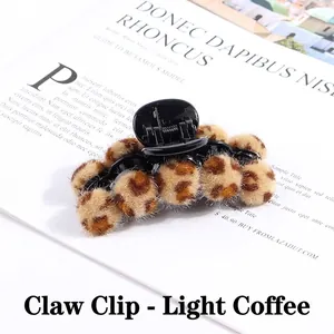 Macro detail of leopard print plush balls and pearl banana clip hair accessory