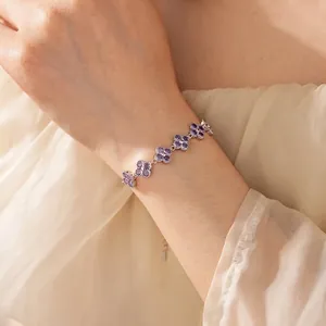 Exquisite silver-tone bracelet with sparkling purple zircon clover charms worn by a model