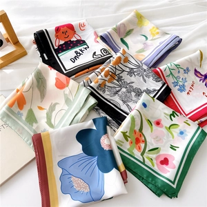 Stack of elegant square satin scarves with diverse floral and illustration prints
