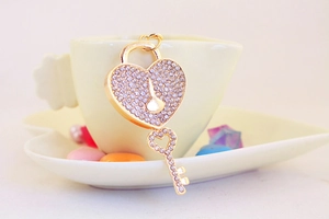 Close-up of gold heart lock and key keychain with sparkling rhinestones on a dish