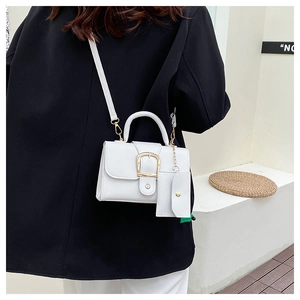 Detailed macro view of white pebble leather texture and gold buckle on a stylish mini handbag
