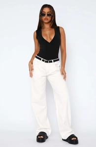 Detailed view of white wide-leg jeans paired with a black plunging bodysuit and belt
