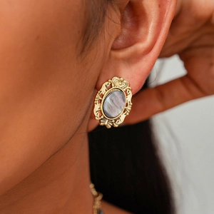 Detailed close-up of retro baroque oval earrings in vintage gold finish on a model