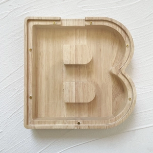 Macro detail of wooden letter B piggy bank with transparent acrylic front and screws