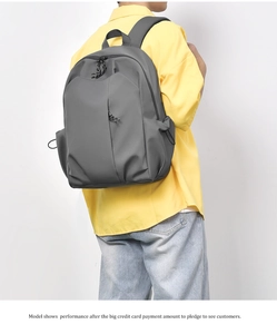 Gray minimalist nylon backpack for students shown on a model against a white wall