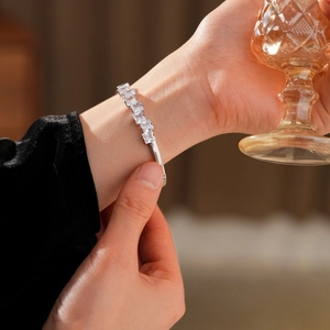 Gros plan d'un bracelet jonc ouvert argenté serti de zircons carrés porté au poignet