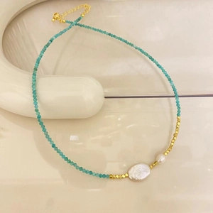 Detail of freshwater baroque pearl and teal beads on a golden clasp necklace