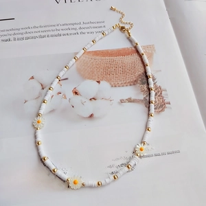 Detail of bohemian daisy beaded necklace with white heishi beads and gold lobster clasp