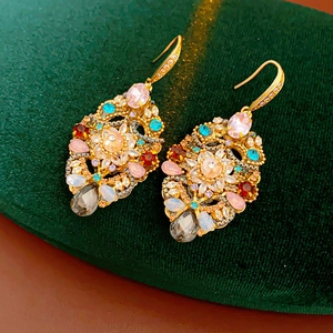 Detailed close-up of vintage drop earrings with colorful crystals on dark velvet