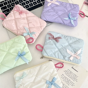 Close-up of quilted bow-accented cosmetic pouches in multiple pastel colors with zipper
