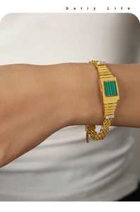 Gros plan d'un bracelet doré multicouche avec pierre verte rectangulaire et cristaux