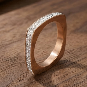 Gros plan d'une bague carrée en or rose sertie de zircons sur fond de bois marron