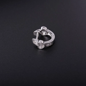 Close-up of a silver heart-shaped earring with zircons on a black textured surface