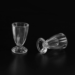 Miniature transparent plastic cream cups with vertical stripes on a black background