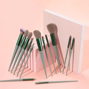 Set of 13 professional makeup brushes with brown bristles and blue handles on pink blocks