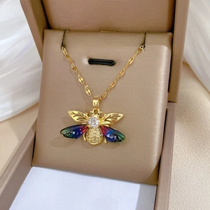 Detail of gold bee pendant with colorful crystal wings on beige jewelry box display