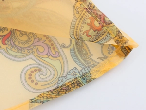 Macro shot of paisley organza fabric showing yellow hem stitching and detailed patterns