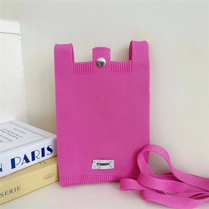 Close-up of bright pink knitted phone bag with silver snap button and brand label