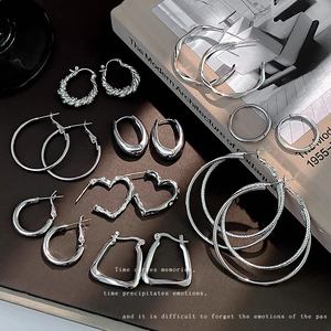 Set di orecchini d'argento con cerchi geometrici e forme a cuore su sfondo scuro