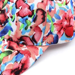 Macro view of cotton baseball cap with colorful abstract floral print and gold glitter edges
