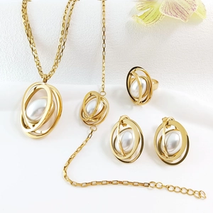 Flat lay of gold jewelry set with white pearls featuring a modern multi-ring design