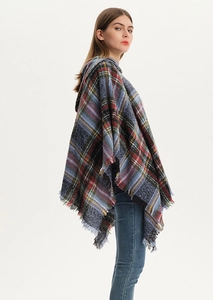 Detail of blue plaid poncho featuring soft textured fabric and fine fringe edge details
