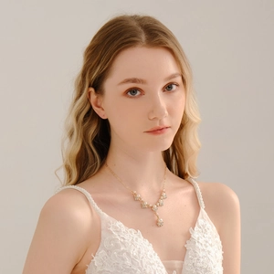 Dettaglio di elegante collana dorata con perle bianche e strass scintillanti per spose
