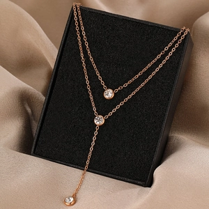 Macro detail of rose gold double-layered titanium necklace with zircon tassels and pendants