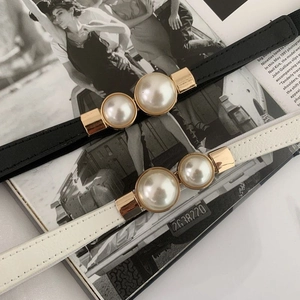 Detail of elegant waist belts featuring large twin pearls and gold metal buckles