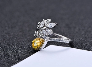 Macro view of silver leaf ring featuring a yellow pear-cut stone and white zircon accents