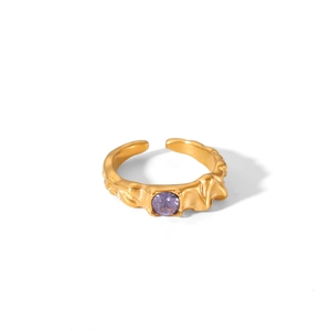 Detail view of gold adjustable ring featuring irregular lava texture and a purple zircon