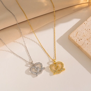 Minimalist gold and silver heart-shaped pendant necklaces with zircon on beige texture