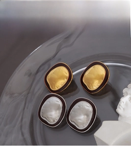 Detail of vintage textured metal earrings with black enamel trim on glass tray