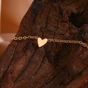 Detailed close-up of a polished 18K gold heart pendant on a metal link chain