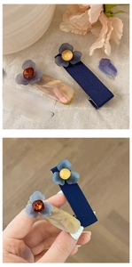 Dettaglio dei fermagli per capelli con fiori blu in tessuto e finitura in resina