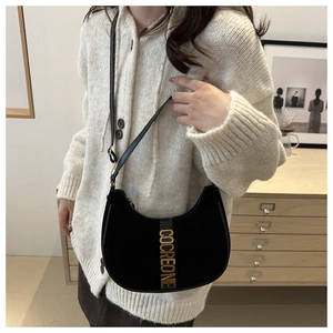 Detail of black crescent shoulder bag with suede texture and gold COCREONE metal hardware