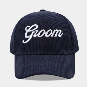Detail view of navy blue corduroy baseball cap with white Groom script embroidery