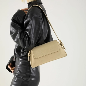 Side view of beige matte PU leather baguette bag showing texture and metal strap buckle