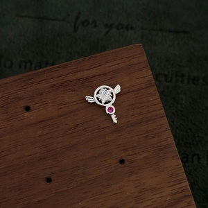 Macro shot of silver star scepter earring with pink gems and zircons on wood